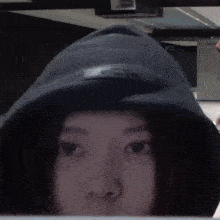a woman in a black hoodie is looking at the camera .