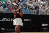 a woman holding a tennis racquet on a tennis court with a sign that says wta 250