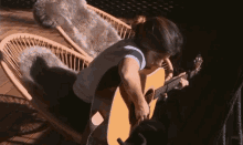 a woman playing an acoustic guitar in a chair