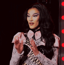 a woman wearing a white lace top with a pink bow on it