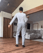 a man is dancing in a living room with a couch