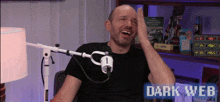 a man is laughing in front of a microphone with the words dark web on the bottom right