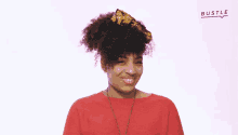 a woman wearing a red shirt is smiling in front of a white background with bustle written on it