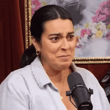 a woman is crying in front of a microphone in front of a picture of flowers .