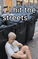 a man is sitting in front of a trash can that says enquiry hotline