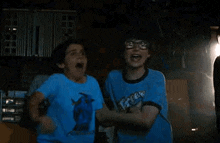 two boys are hugging each other in a dark room .
