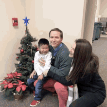 a man and woman are posing for a picture in front of a christmas tree