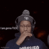 a man wearing headphones and a thrasher hoodie is sticking out his tongue .