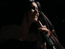 a woman singing into a microphone with a pearl necklace on
