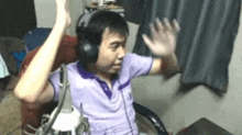 a man wearing headphones is sitting in a chair with his arms in the air .