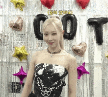 a woman stands in front of balloons and a sign that says t.