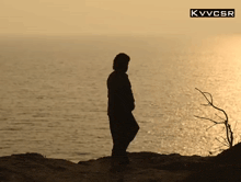 a silhouette of a person standing on a cliff overlooking a body of water with kvvcsr written on the bottom