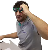 a man wearing a shirt that says silbeck holds up a pair of green sunglasses
