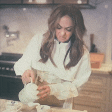 a woman in a white shirt is pouring tea into a white cup