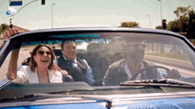 a group of people are riding in a blue car with the letters h on the bottom