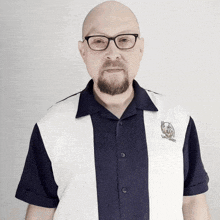 a bald man with a beard wearing glasses and a bowling shirt