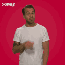 a man in a white t-shirt is making a funny face in front of a red background that says swr3