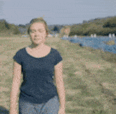 a woman in a black shirt is standing in a field with a river in the background .