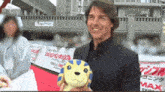 a man holding a stuffed animal in front of a sign that says tokyo tokyo