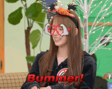 a woman wearing a headband with mickey mouse glasses and the word bummer on it