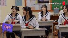 a group of girls are sitting at desks in a classroom and one of them has the name lya on it