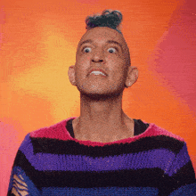 a man with a mohawk and a striped sweater looks up