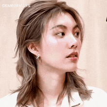 a close up of a woman 's face with a white shirt and earrings .