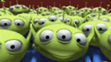 a bunch of green aliens from toy story are looking at the camera .
