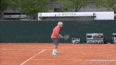 a man in a red shirt is holding a tennis racket on a tennis court