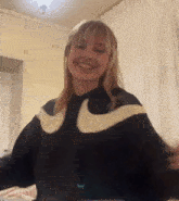 a woman is wearing a black nike sweatshirt and smiling