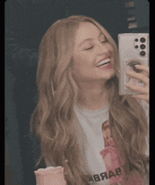 a woman taking a picture of herself with a phone case that says ' abbab ' on it
