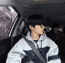a man wearing glasses is sitting in a car with a seat belt around his neck