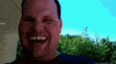 a man in a blue shirt is smiling with his eyes closed .