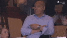 a man in a blue shirt is sitting in front of a tv screen that says sports 2