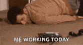 a man is laying on the floor next to a telephone and the words `` me working today '' .