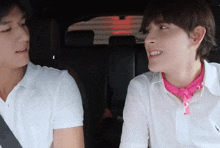 a man wearing a pink bandana is sitting next to another man in a car