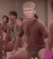 a group of people are doing exercises in a gym while a man with donald trump 's face on his face .