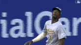 a baseball player wearing a oakland athletics jersey throws a ball