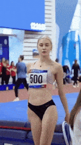 a woman in a bikini is wearing a number 500 tag on her chest .
