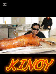 a man in sunglasses stands in front of a pig that says kinoy on the bottom right