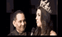 a woman wearing a crown is talking to a man in a suit and bow tie .