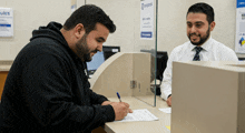 a man in a black hoodie is signing a form