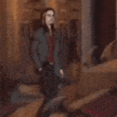 a man in a suit and red shirt is standing in front of a building .