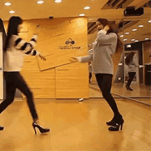two women are dancing in a room with a sign that says rainbow bridge on it