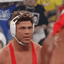a man wearing a red shirt and a white headgear looks at another man