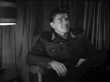 a black and white photo of a man in a military uniform sitting in a chair