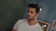 a man with a beard wearing a white shirt looks at the camera