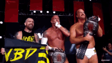 three men holding wrestling belts and a banner that says vbd