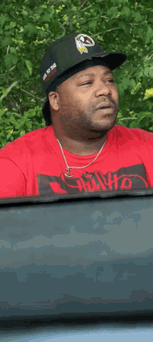 a man wearing a black hat and a red shirt that says chave