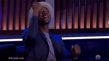 a man is sitting on a couch with his arms in the air and the words #songland on the bottom